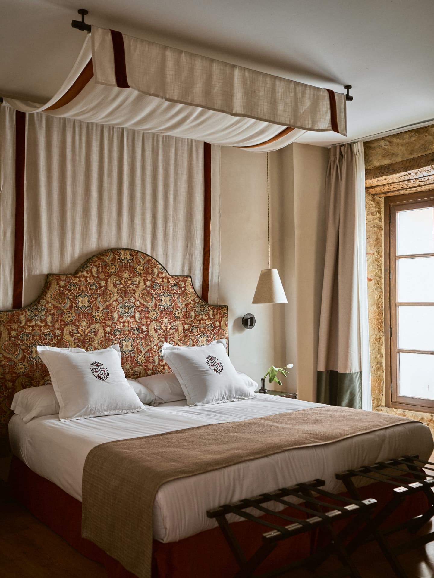 Suite del Hotel Posada Convento San Esteban de Gormaz con cama con dosel y muro de piedra